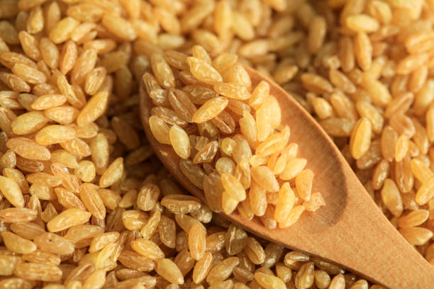 Bulgur, raw wheat grains in wooden bowl stock photo