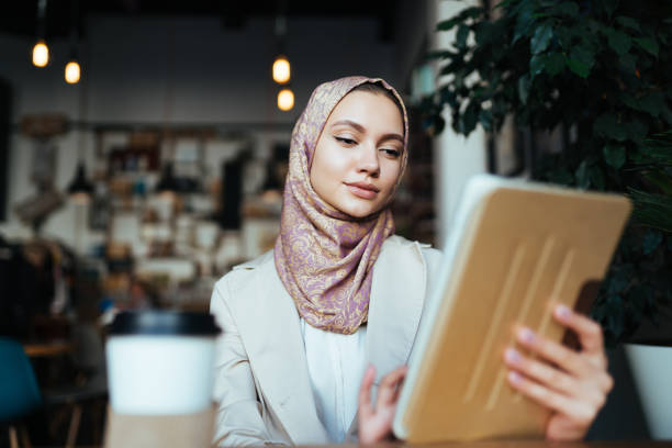A woman in Muslim clothes and a scarf works in a cafe A woman in Muslim clothes and a scarf works in a cafe arab woman stock pictures, royalty-free photos & images