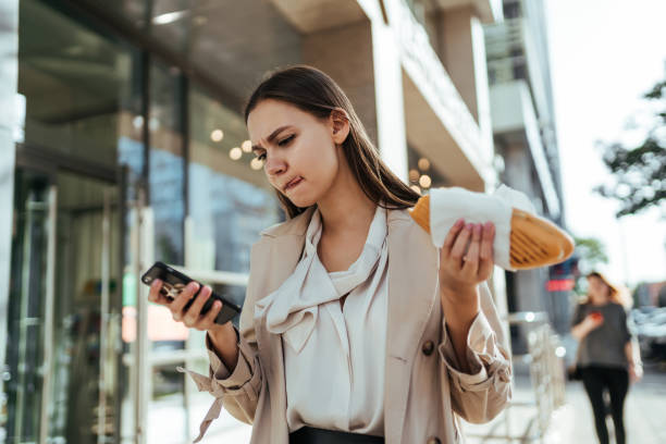 занятая бизнесвумен, работающая онлайн на смартфоне во время перерыва - food currency breakfast business стоковые фото и изображения