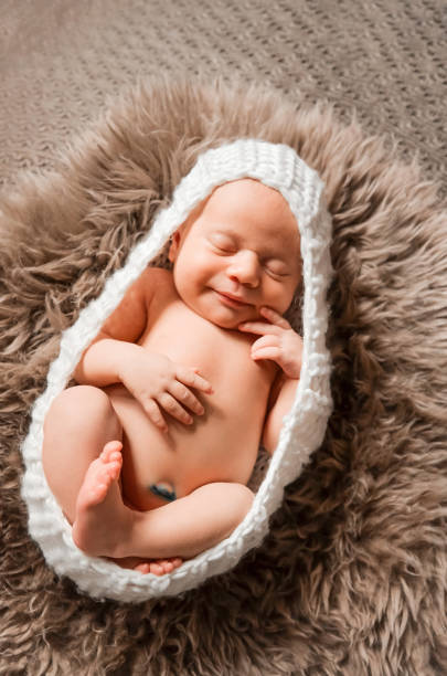 istock A cute, newborn baby in a sleeping cocoon. Smiling Mona Lisa Tinted Selective focus A tender smile of the baby. 1096044532