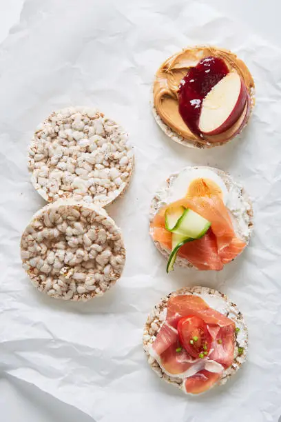 Variation of healthy gluten free rice cakes with fruit, vegetables, meat, salmon and sweets viewed from above