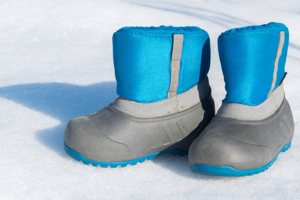 Pair of waterproof children boots on the snow, space for text