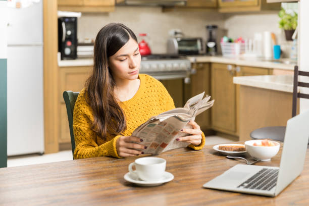 istock Woman Reading Newspaper While Having Morning Meal 1096066384