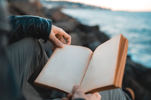 istock Man holding an empty old book by the sea 1096070064