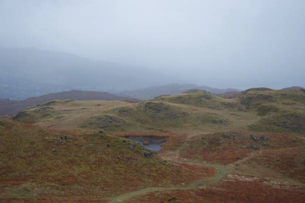 camino a través del moorland otoñal hacia el lago de valle. niebla en las montañas en la distancia. - scotland texas fotografías e imágenes de stock