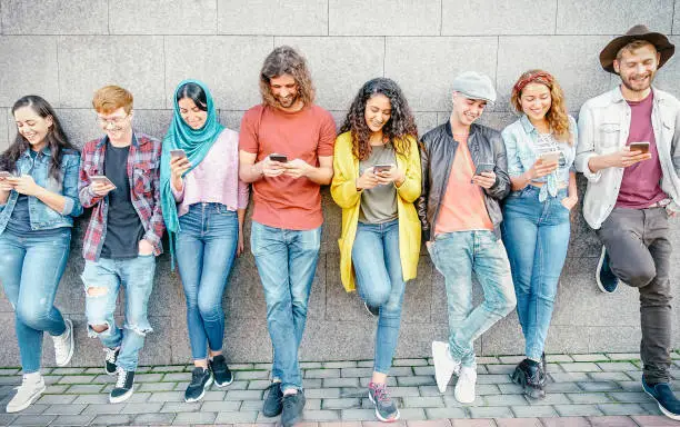 Photo of Group of fashion friends watching on their smart mobile phones - Millennial generation z addicted to new technology trends - Concept of people, tech, social media, friendship and youth lifestyle