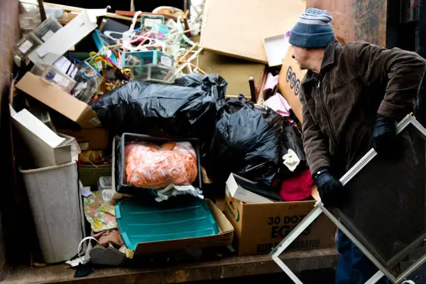 Photo of Workman loading junk in dumpster