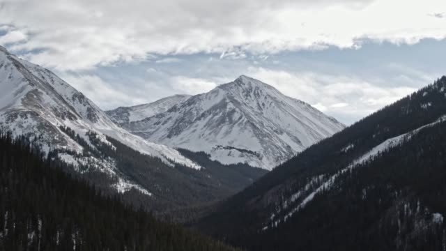 Aerial Drone Shot of Snowcapped Mountains of the Rocky Mountains in Colorado under a Partially Cloudy but Sunny Winter Sky