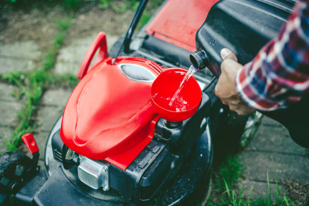 man refuelling a lawn mower in his back yard - lawn mower red plant lawn imagens e fotografias de stock