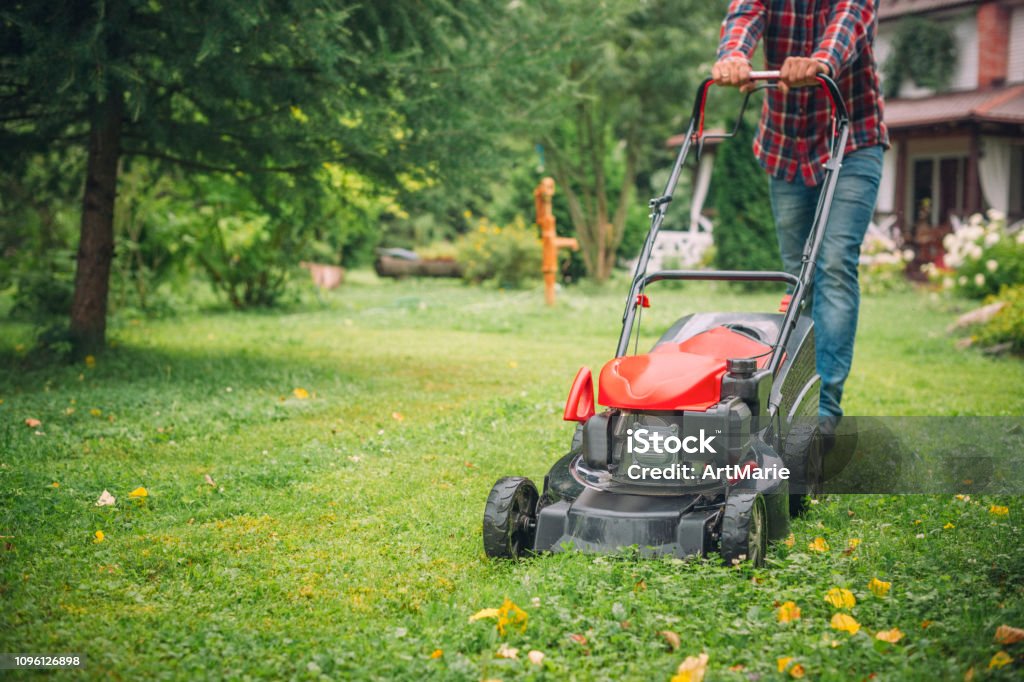 Man using a lawn mower in his back yard Man mowing grass near his house Lawn Mower Stock Photo