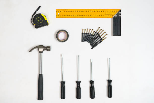 Top view of screwdrivers and tape measure on white backdrop