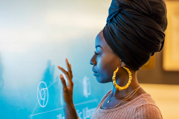 Young African-American woman using interactive display A young African-American woman in her 20s wearing a turban and large earrings, touching a giant interactive display screen. huge black woman pictures stock pictures, royalty-free photos & images