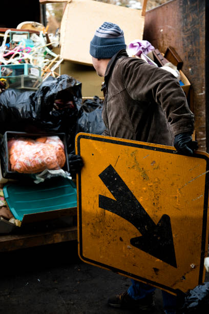 istock Workman tossing old road sign in dumpster 1096140064