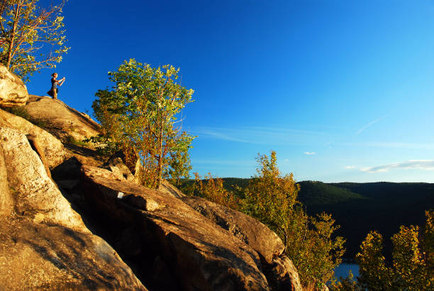 Cold Spring, NY, USA August 23, 2011 A young woman photographs the view from the top of Breakneck Ridge in the Hudson Highlands near Cold Spring, New York
