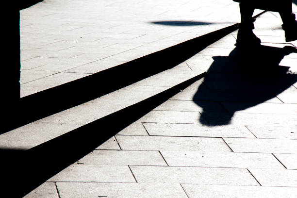 istock Blurry silhouette shadow of a person walking on a city sidewalk with steps  in black and white 1096185444