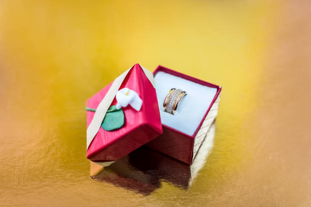 anel de ouro em caixa de presente vermelha sobre fundo dourado - day gem ring open - fotografias e filmes do acervo