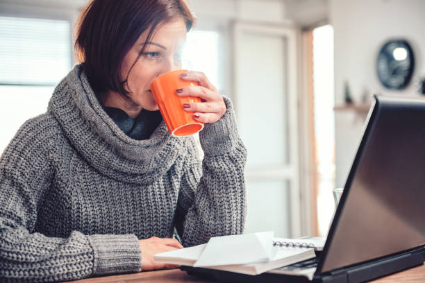 istock Woman drinking coffee and working on laptop 1096218270