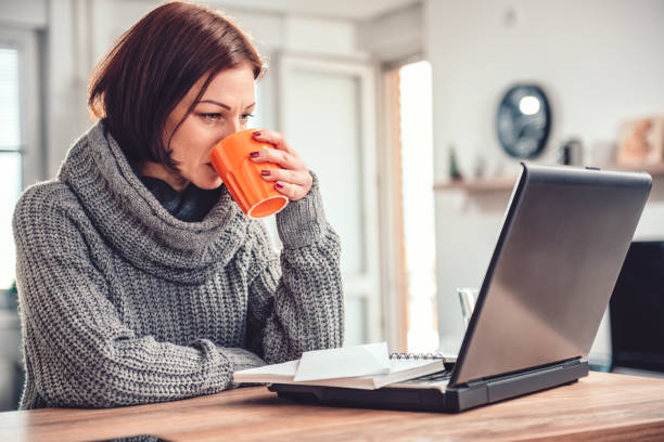 istock Woman drinking coffee and working on laptop 1096218376