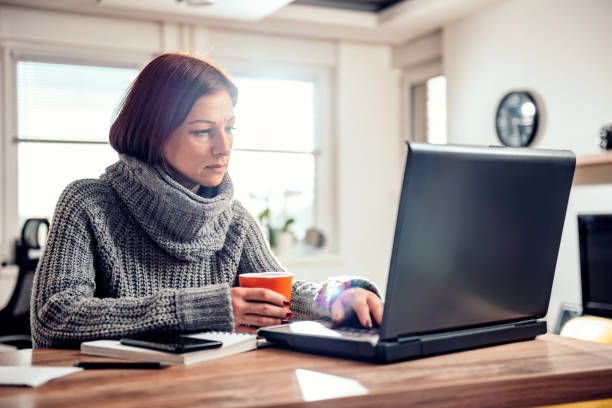 istock Woman using laptop and drinking coffee 1096222386