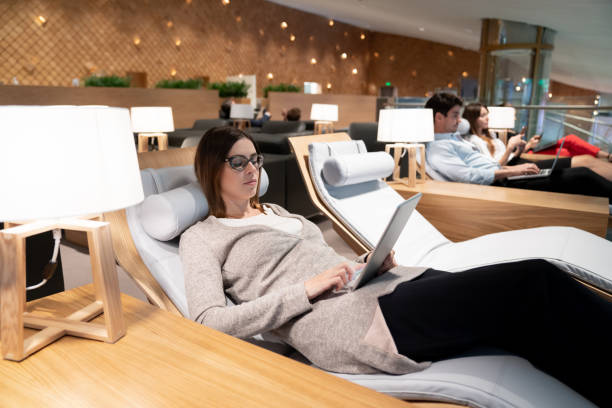 Traveling business woman relaxing in a VIP lounge at the airport Traveling business woman relaxing in a VIP lounge at the airport using her tablet computer while waiting for her flight - travel concepts airport departure area stock pictures, royalty-free photos & images