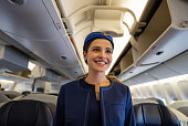 Friendly flight attendant smiling on the aisle in an airplane