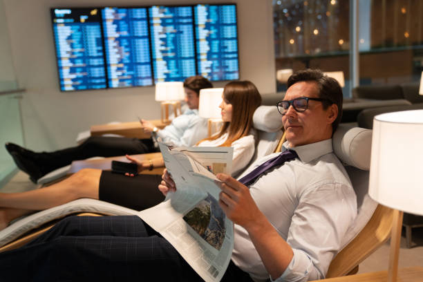 business-mann liest zeitung in einer vip-lounge am flughafen reisen - airport newspaper travel business travel stock-fotos und bilder