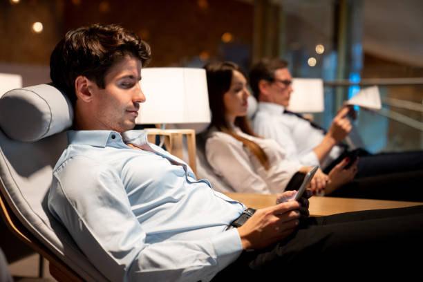 Traveling business man relaxing in a VIP lounge at the airport Traveling business man relaxing in a VIP lounge at the airport texting on their phone while waiting for his flight - travel concepts airport departure area stock pictures, royalty-free photos & images