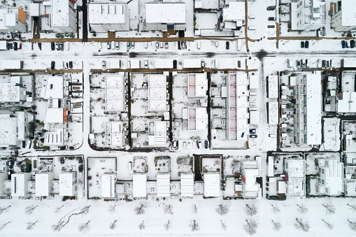 Abstract pattern of rows of houses, apartment buildings, streets and trees in winter from above.