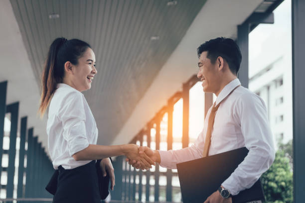istock Two asian business people standing and shaking hands with together. 1096264356