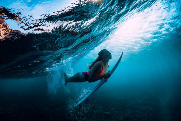istock Attractive surfer woman dive underwater with under wave and sun light. 1096268896