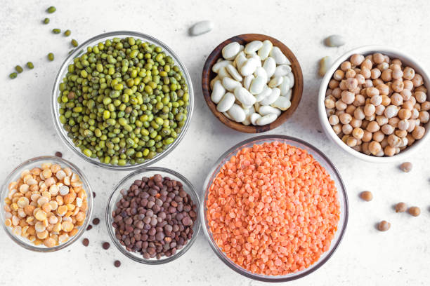 Assortment of colorful legumes Healthy food, dieting, nutrition concept, vegan protein source. Assortment of colorful legumes in bowls, lentils,  kidney beans, chickpeas, mung, peas on white background, top view, copy space. red mung bean stock pictures, royalty-free photos & images