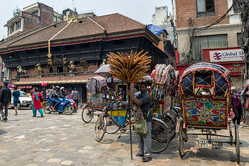 Kathmandu, Nepal - April 16, 2016: Group of rickshaws by the street at Asan Tole Market which is busy with workers, local and tourists.