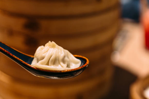 istock Xiao Long Bao (Soup Dumpling) in spoon with blur bamboo streamer basket in background. 1096340874