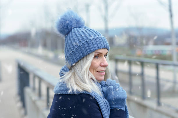 istock Pretty blond woman standing in falling winter snow 1096382102