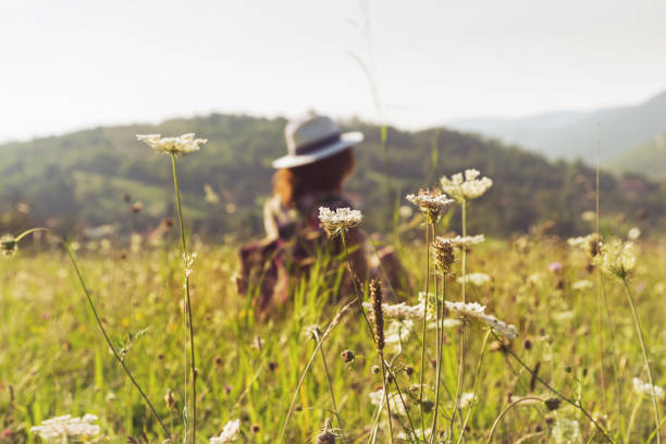 Young girl traveler relaxing in nature. Traveler with backpack in nature. Girl traveler relaxes in fields in summer day. Traveler. Summer. Backpack. Girl. Fields. Nature