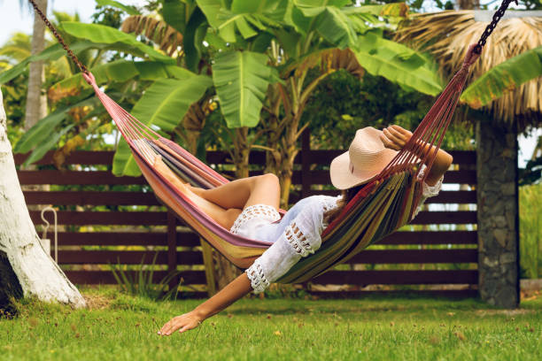 Attractive sexy woman relaxing in hammock. Beautiful woman sleeping in hammock. Happy beautiful woman in white dress relaxing in hammock. Beautiful woman in vacation. Vacation. Hammock. Tropical garden. hammock relaxation women front or back yard stock pictures, royalty-free photos & images