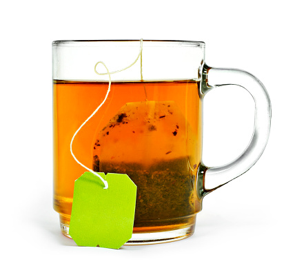 Cup of tea with tea bag and copy space, isolated on white background. Hot drink, herb tea or assam or earl grey tea. Cut out object.