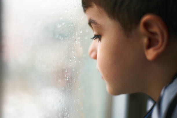 istock Little boy watching the rain through the window 1096413306
