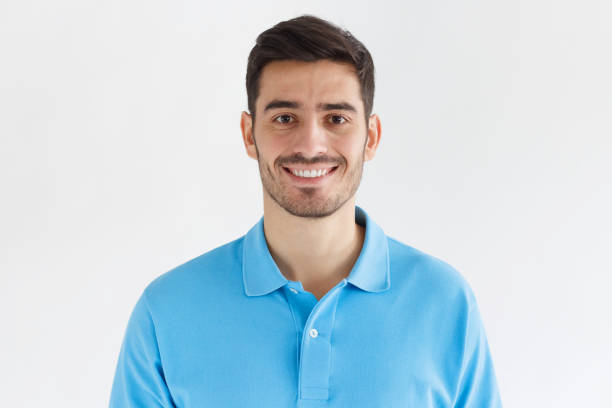 retrato de joven sonriente a hombre guapo en camiseta polo azul aislado sobre fondo gris de cerca - clothing front view head and shoulders horizontal fotografías e imágenes de stock