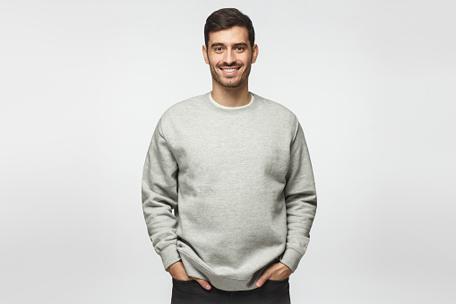 Young handsome man in gray sweatshirt, standing isolated on background