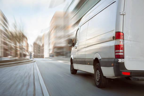 White transporter driving inside the city A fast moving white van on a bright street with high buildings. Motion blurred background. east germany photos stock pictures, royalty-free photos & images