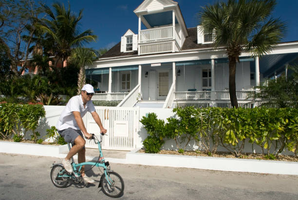 Bahamas Man in a bicycle and loyalist home. Bay Street. Dunmore Town, Harbour Island, Eleuthera. Bahamas dunmore town stock pictures, royalty-free photos & images