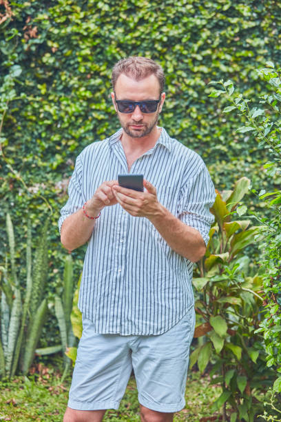 istock Man with sunglasses and summer shirt using smartphone. 1096444626