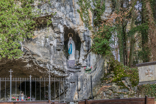 beautiful image of the replica of the Virgin of Lourdes in a natural grotto with a metal fence in Vielsalm on a wonderful autumn day in the Belgian Ardennes