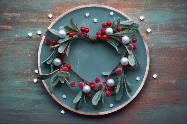 istock Red mistletoe Christmas wreath on round decorative tray on matching textured background 1096467026