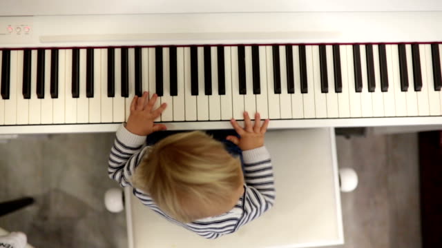 Sweet positive toddler child playing piano. Early music education for little kids.