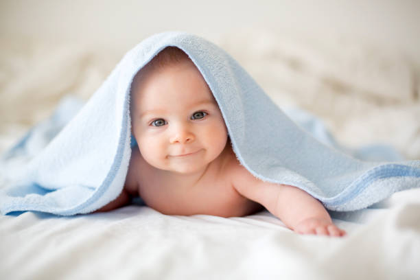 istock Cute little baby boy, relaxing in bed after bath, smiling happily 1096476268