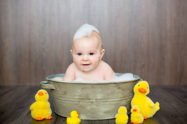istock Cute baby playing with rubber duck while sitting in metal basin 1096476566