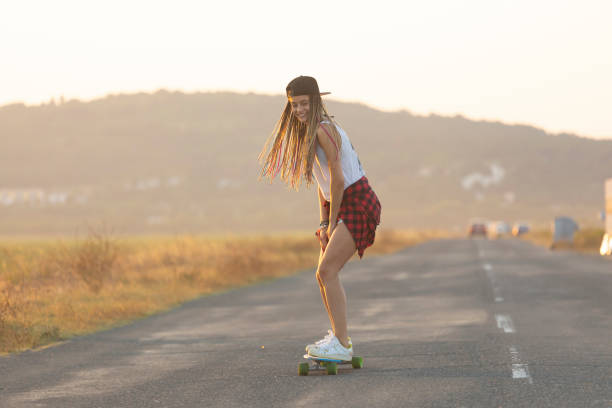 istock Beautiful girl with longboard skating on road 1096476642