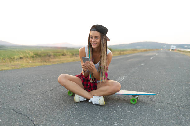 istock Beautiful girl with longboard social networking on road 1096476650